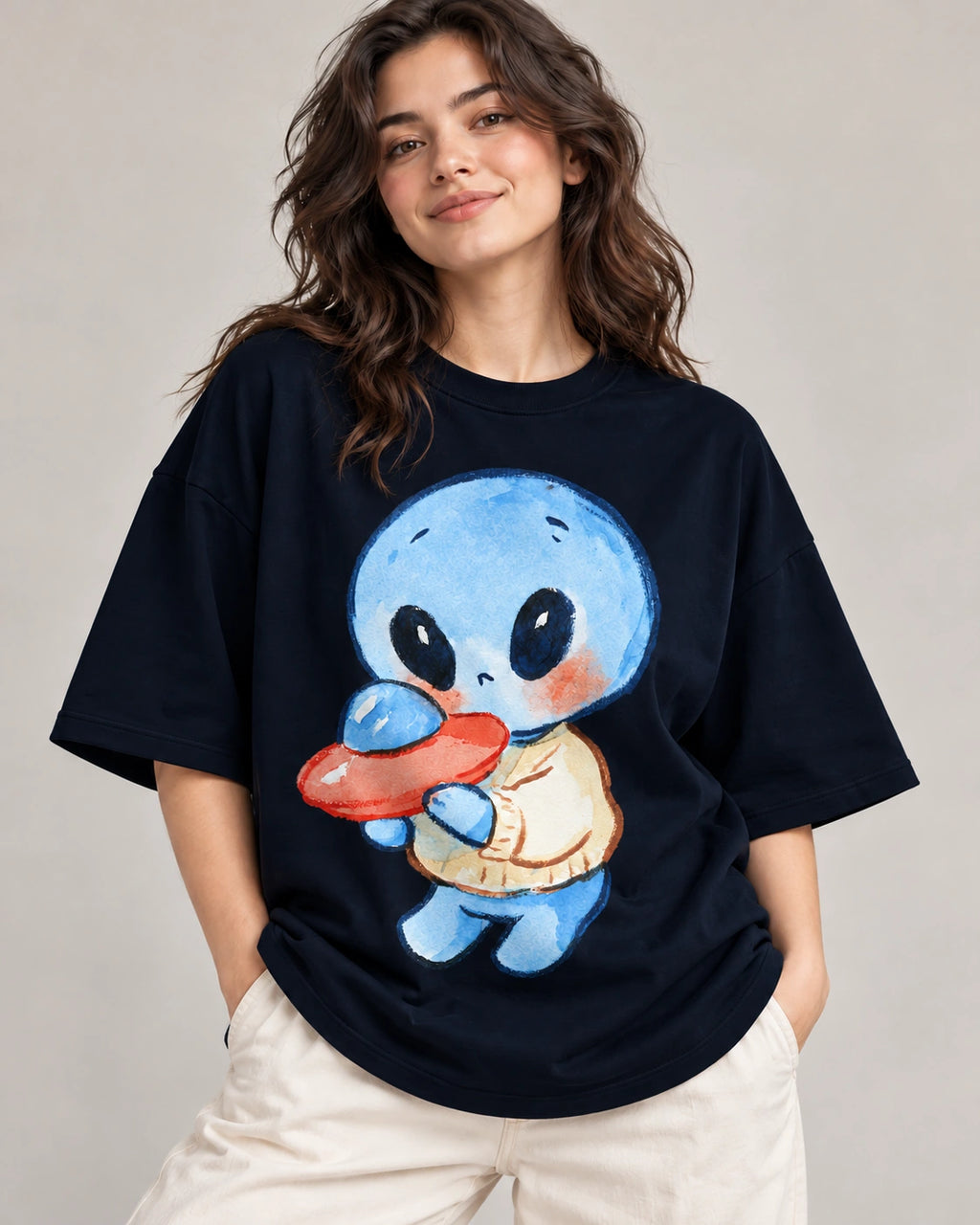 Woman in a navy blue oversized French terry t-shirt printed with a blue alien in a sweater hugging a small red UFO