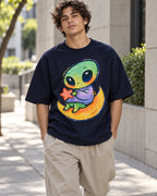 Man on a street in a navy blue oversized French terry t-shirt with a green alien hugging a red star on a crescent moon