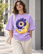 Woman on a street in a lavender oversized French terry t-shirt with a fluffy one-eyed purple monster on a yellow moon