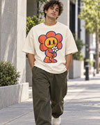Man on a street in an off-white oversized French terry t-shirt with a smiling orange flower character holding a daisy