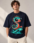 Man in a navy blue oversized French terry t-shirt printed with a teal sea serpent rising from a wave