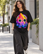 Woman on a street in a black oversized French terry t-shirt with a smiling rainbow crystal creature with big round eyes