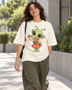 Woman on a street in an off-white oversized French terry t-shirt with a green alien in an apron pouring tea from a teapot