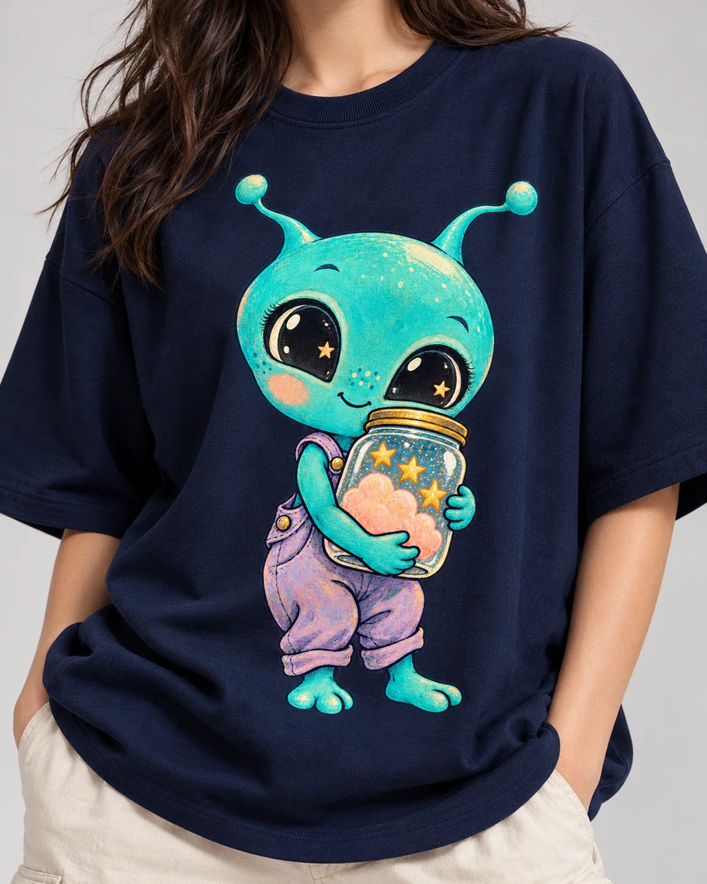 Close-up of an aqua alien hugging a jar of pink clouds and stars printed on a navy blue oversized French terry t-shirt