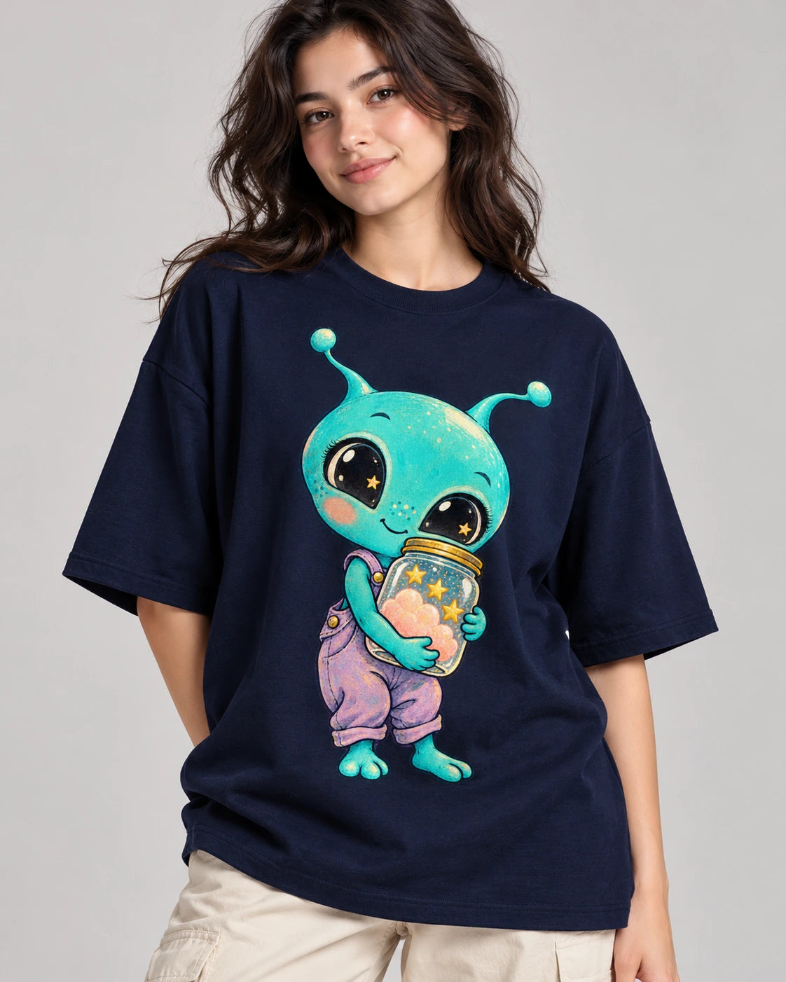 Woman in a navy blue oversized French terry t-shirt printed with an aqua alien hugging a jar of pink clouds and stars