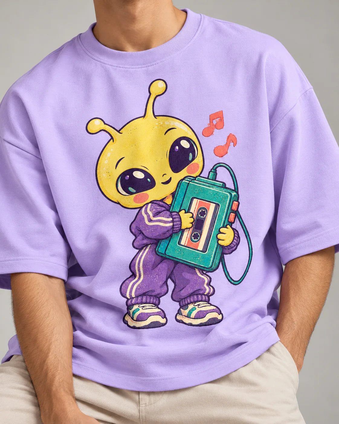 Close-up of a yellow alien in a tracksuit holding a cassette player printed on a lavender oversized French terry t-shirt