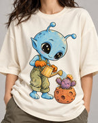 Close-up of a blue alien watering a cactus in a meteor-like pot printed on an off-white oversized French terry t-shirt
