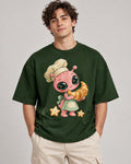 Man in a bottle green oversized French terry t-shirt printed with a pink alien chef carrying a giant croissant