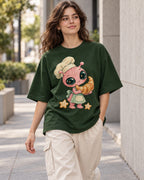 Woman on a street in a bottle green oversized French terry t-shirt with a pink alien chef carrying a giant croissant